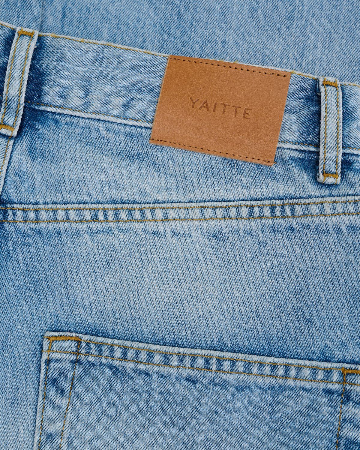 Dark denim jeans leather patch detail flat lay photography